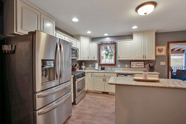 kitchen with light hardwood / wood-style floors, plenty of natural light, stainless steel appliances, and sink