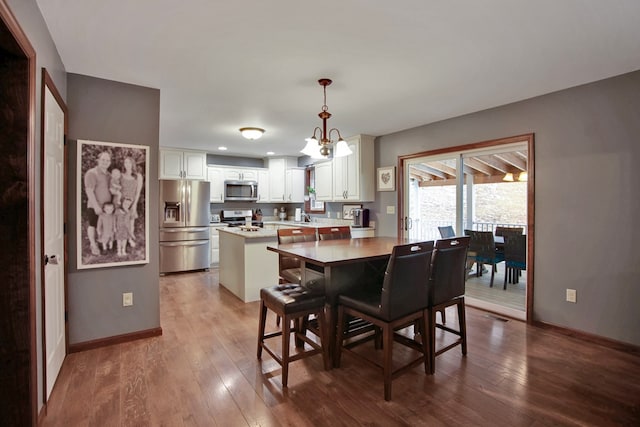 dining space with sink, an inviting chandelier, and wood-type flooring