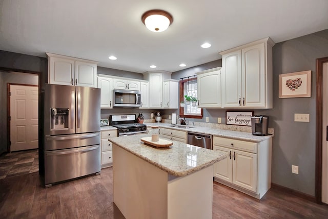 kitchen featuring stainless steel appliances, light stone counters, a center island, dark hardwood / wood-style flooring, and sink