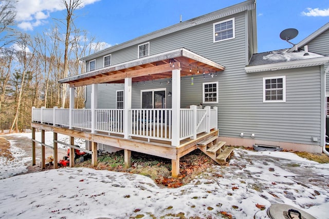 snow covered rear of property featuring a deck