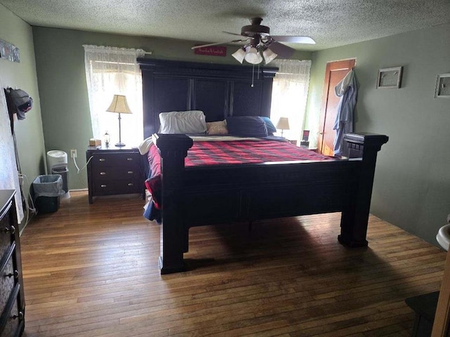 bedroom featuring multiple windows, a textured ceiling, ceiling fan, and dark wood-type flooring