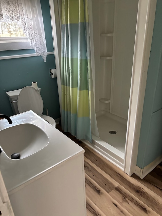 bathroom featuring toilet, a shower stall, a sink, and wood finished floors