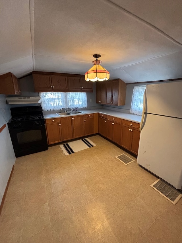 kitchen featuring light floors, freestanding refrigerator, black range with gas stovetop, under cabinet range hood, and a sink