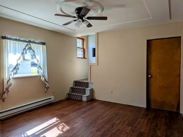 spare room with ceiling fan, baseboard heating, and dark wood-type flooring