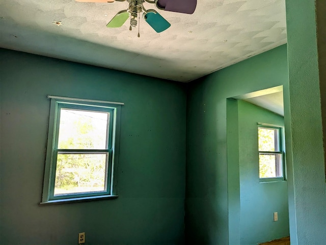 empty room with a textured ceiling, plenty of natural light, and ceiling fan