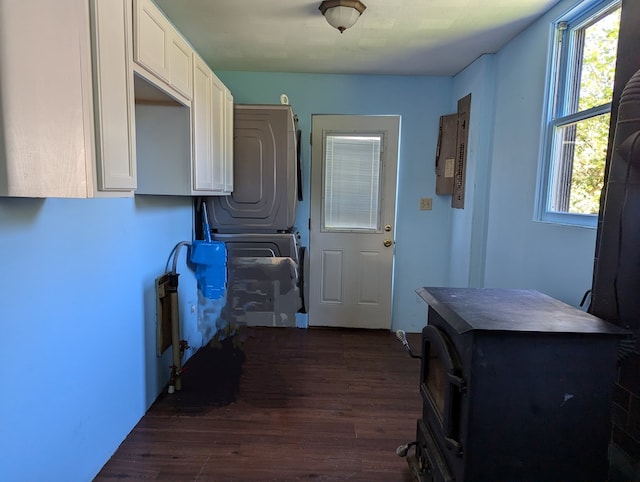 laundry area with electric panel, stacked washer / dryer, and dark wood-type flooring