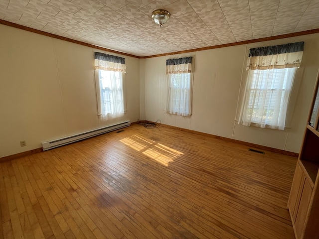 empty room with light wood-type flooring, baseboard heating, and crown molding