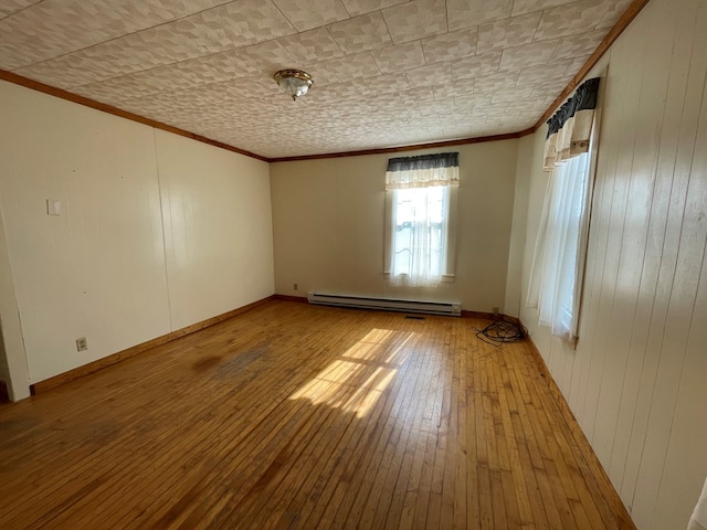 spare room featuring light hardwood / wood-style flooring, ornamental molding, and baseboard heating