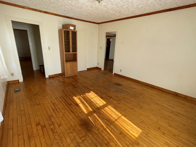 empty room featuring hardwood / wood-style flooring and ornamental molding