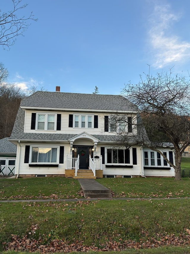 view of front of home featuring roof with shingles and a front yard