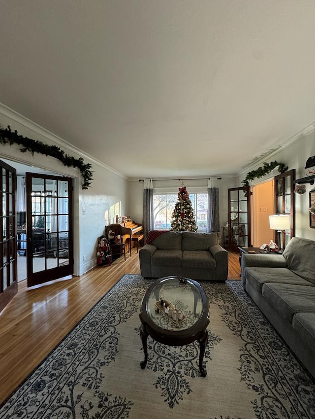 living area with french doors, crown molding, baseboards, and wood finished floors