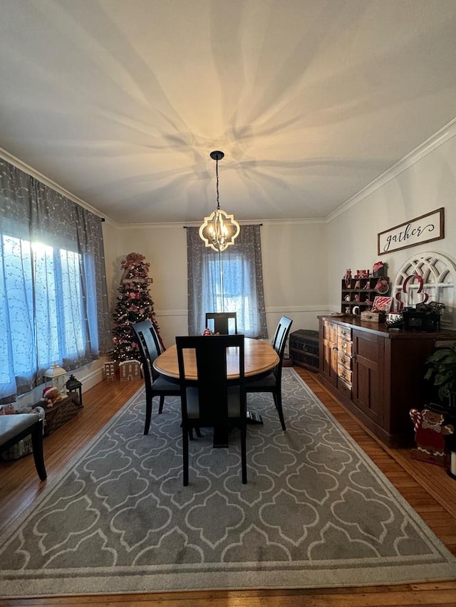 dining area featuring an inviting chandelier, ornamental molding, and wood finished floors