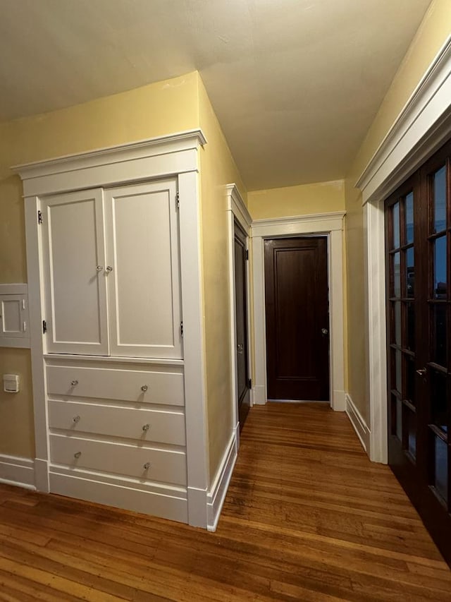 corridor featuring dark wood finished floors and baseboards