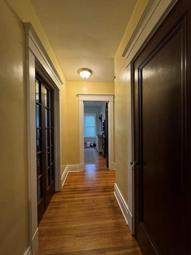 corridor featuring baseboards and wood finished floors