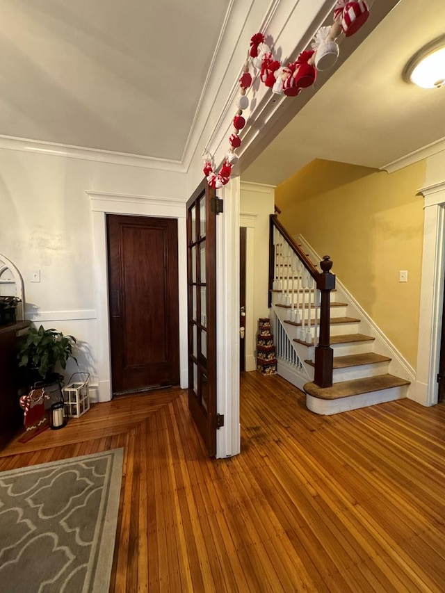 entryway featuring wood finished floors, crown molding, and stairs