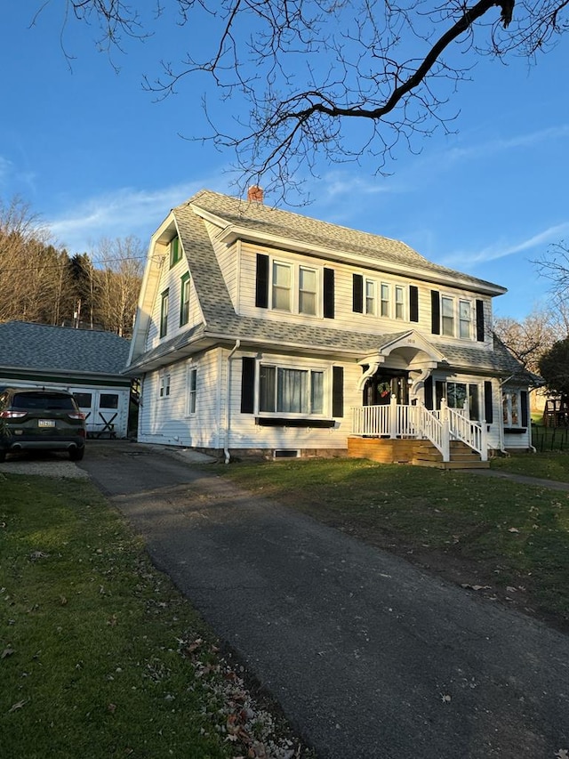 view of front of house with a shingled roof, an outdoor structure, a gambrel roof, driveway, and a chimney