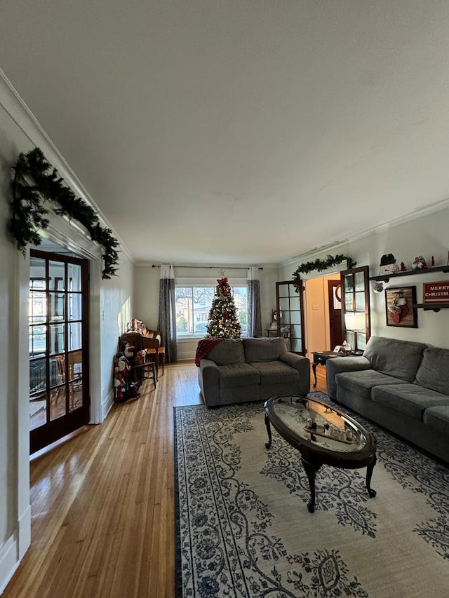 living room with crown molding, baseboards, and light wood-style floors