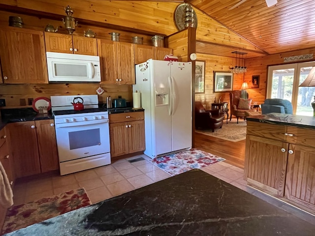 kitchen with lofted ceiling, wood walls, light tile patterned flooring, and white appliances