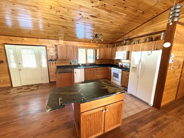 kitchen with white appliances, sink, a center island, wood walls, and wood ceiling