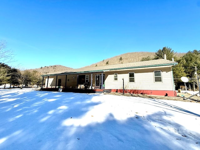 snow covered house featuring a mountain view and a porch