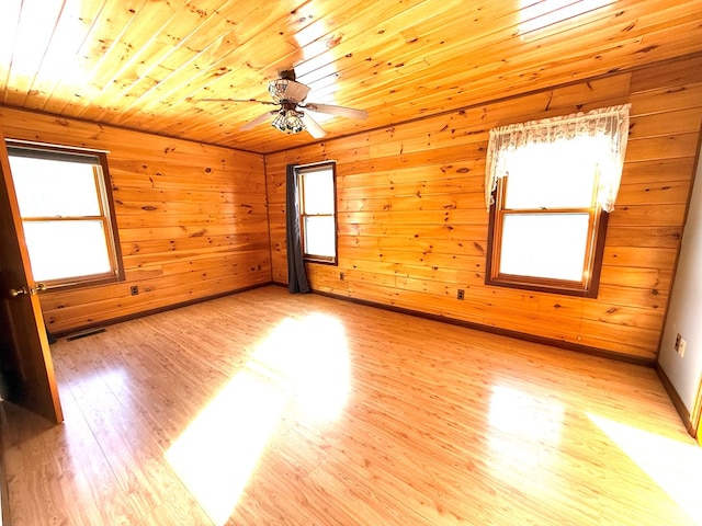 unfurnished room featuring a healthy amount of sunlight, light hardwood / wood-style flooring, ceiling fan, and wooden ceiling