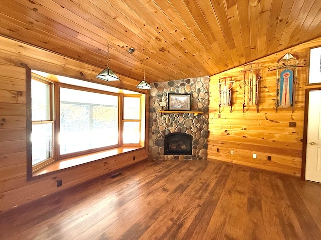 unfurnished living room featuring hardwood / wood-style flooring, wood ceiling, wood walls, a stone fireplace, and vaulted ceiling