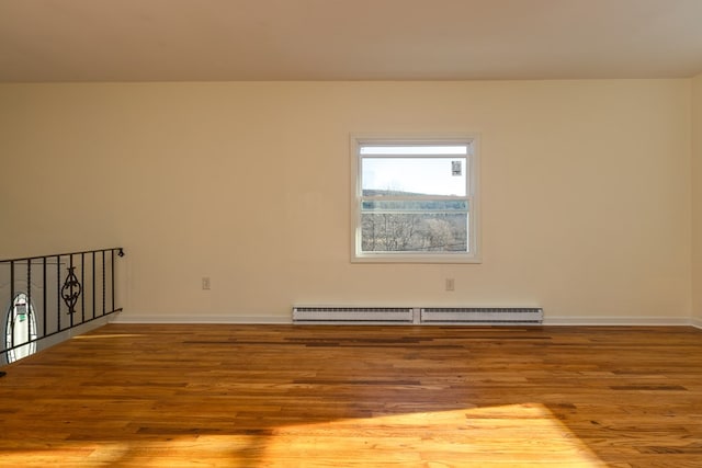 unfurnished room with hardwood / wood-style floors and a baseboard radiator