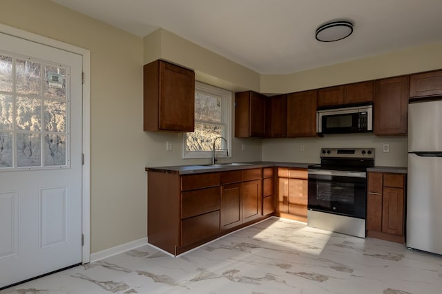 kitchen featuring a wealth of natural light, refrigerator, stainless steel electric stove, and sink