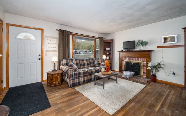 living room featuring dark hardwood / wood-style floors and a brick fireplace