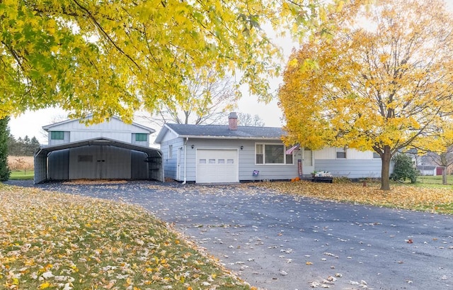 view of front of house with a garage, aphalt driveway, a detached carport, and a chimney