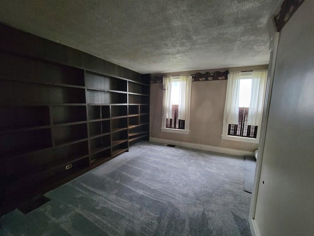 carpeted spare room featuring built in features and a textured ceiling