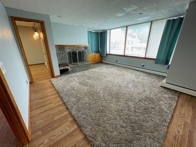 401 Center St, Ulysses, PA 16948 - unfurnished living room with a fireplace with raised hearth, a baseboard heating unit, and wood finished floors