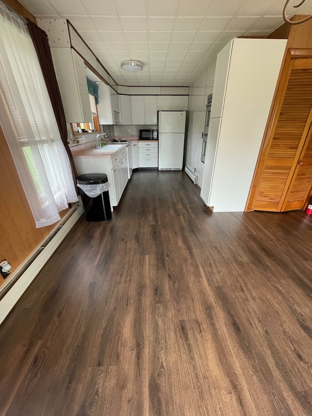 401 Center St, Ulysses, PA 16948 - kitchen with freestanding refrigerator, dark wood-style flooring, light countertops, white cabinetry, and black microwave