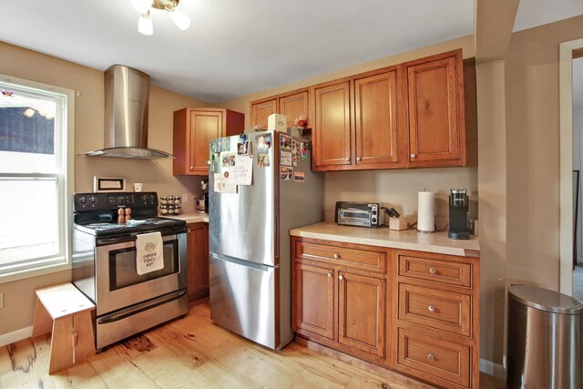 40 Wetmore St, Wellsboro, PA 16901 - kitchen with stainless steel appliances, wall chimney range hood, brown cabinetry, light countertops, and light wood-style floors