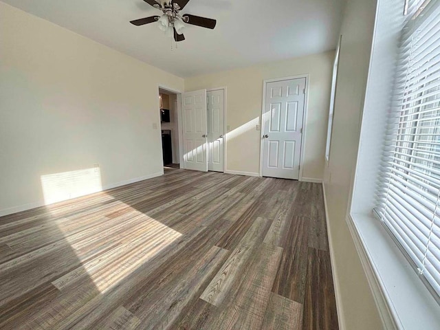 unfurnished bedroom featuring dark hardwood / wood-style flooring, ceiling fan, and multiple closets