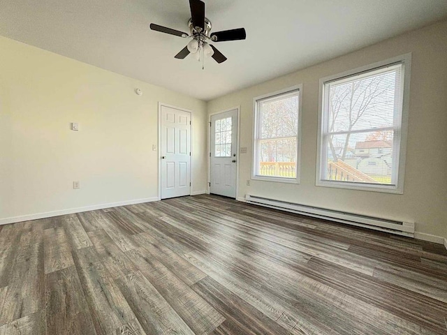 unfurnished room with a wealth of natural light, a baseboard radiator, ceiling fan, and dark hardwood / wood-style floors