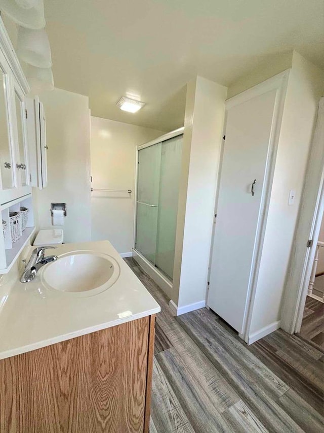 bathroom featuring hardwood / wood-style floors, vanity, and a shower with shower door