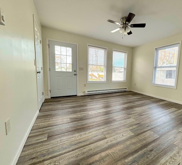 interior space with baseboard heating, a wealth of natural light, ceiling fan, and dark hardwood / wood-style floors