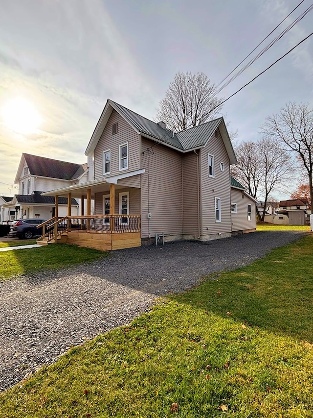 back of property featuring covered porch and a yard