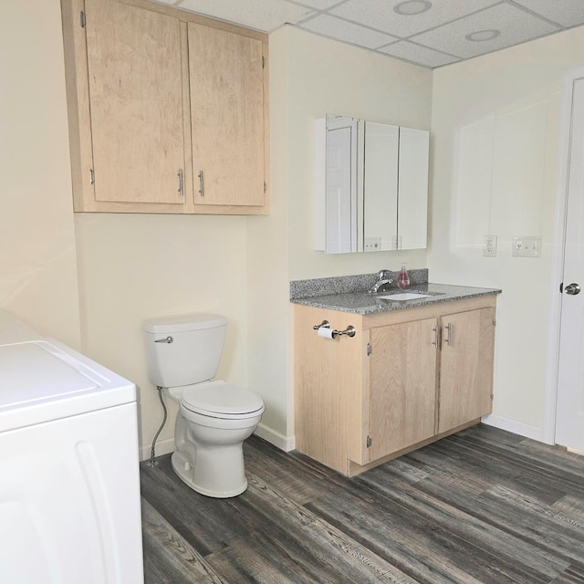 bathroom featuring a drop ceiling, vanity, washer and dryer, hardwood / wood-style flooring, and toilet