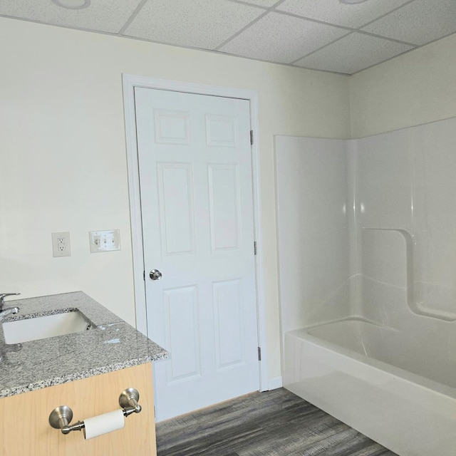 bathroom with a paneled ceiling, vanity,  shower combination, and hardwood / wood-style flooring