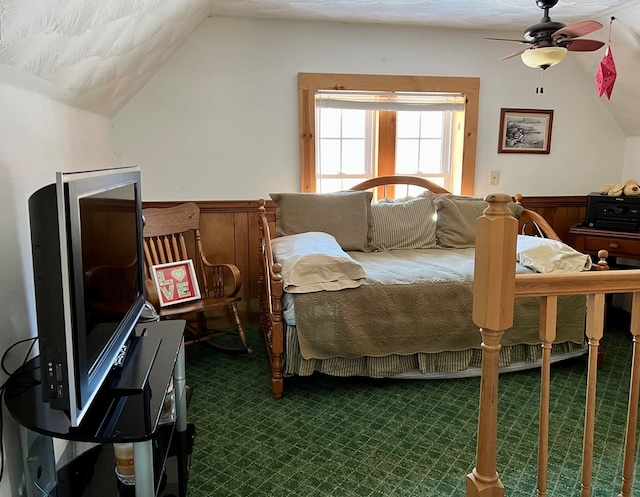 carpeted bedroom featuring ceiling fan, wooden walls, and vaulted ceiling