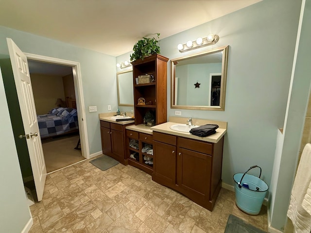 full bathroom featuring ensuite bath, two vanities, stone finish floor, and a sink