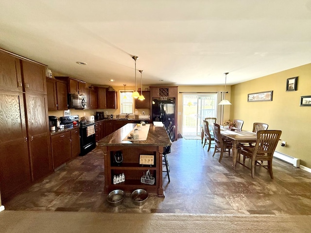 kitchen featuring a center island, dark countertops, a kitchen bar, decorative light fixtures, and black appliances