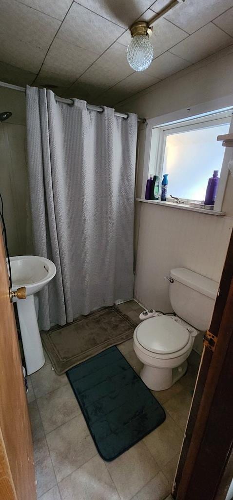 bathroom featuring curtained shower, toilet, and tile patterned flooring