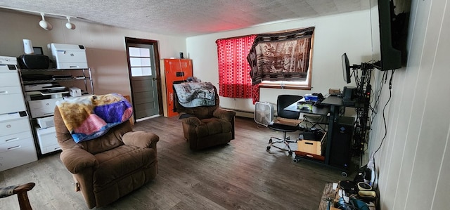 living room featuring wood finished floors, track lighting, and baseboard heating