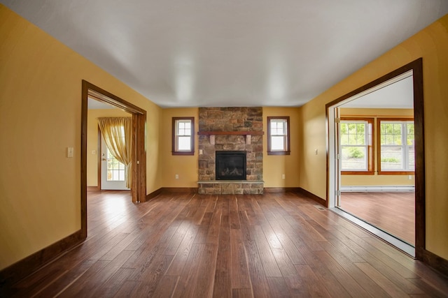 77 Hunters Trl, Wellsboro, PA 16901 - unfurnished living room with healthy amount of natural light, a stone fireplace, baseboards, and dark wood-style floors