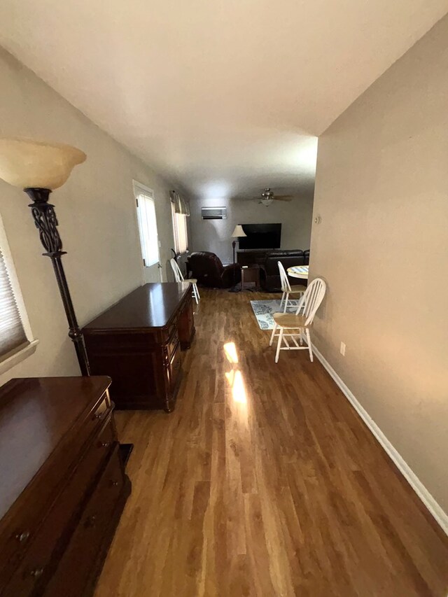 living room with a wall unit AC, ceiling fan, and dark wood-type flooring