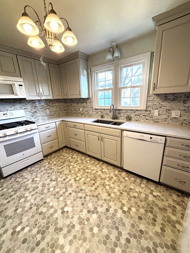 kitchen with sink, pendant lighting, white appliances, and an inviting chandelier