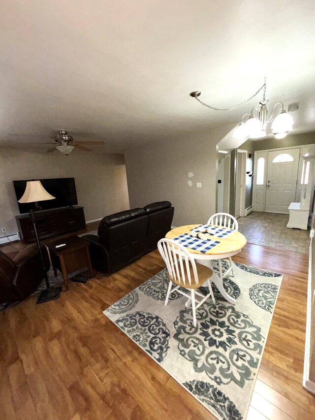 dining space featuring ceiling fan with notable chandelier and hardwood / wood-style flooring